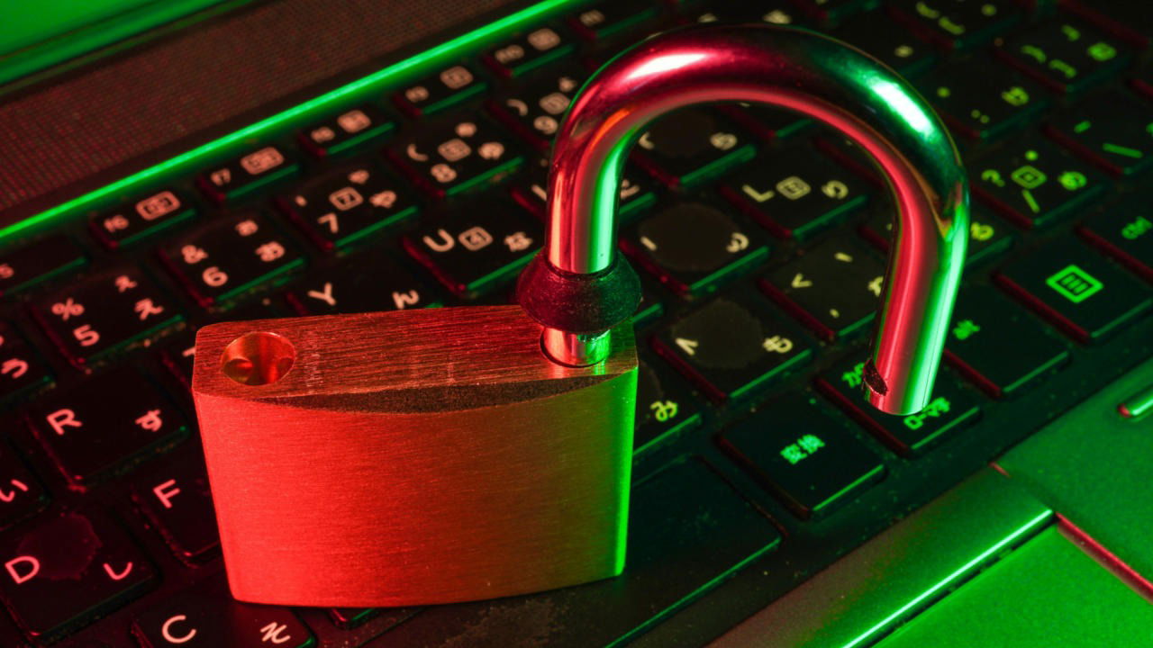 A photograph of a brass lock on top of a laptop keyboard.