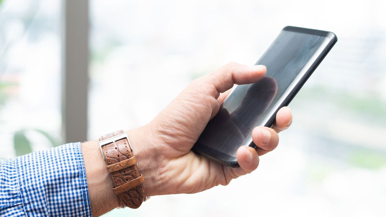 Closeup Of Man Holding Smartphone And Tapping On Its Screen