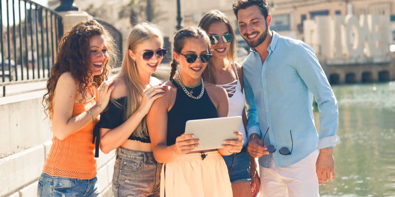 Group of people looking at a tablet near the water.