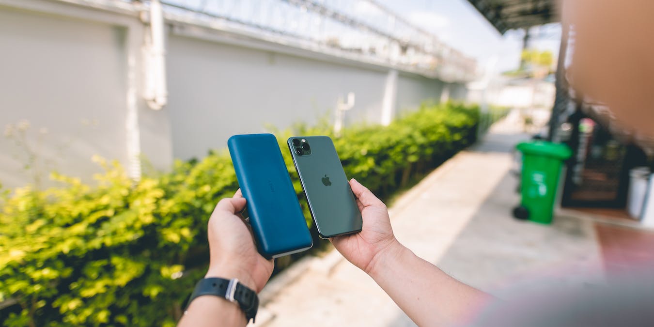 Man holding power bank up to phone outside airport.