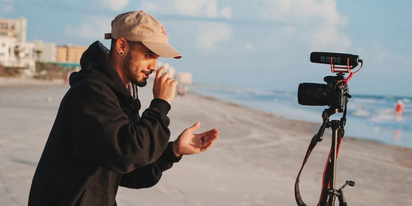 Male vlogger on the beach filming himself.