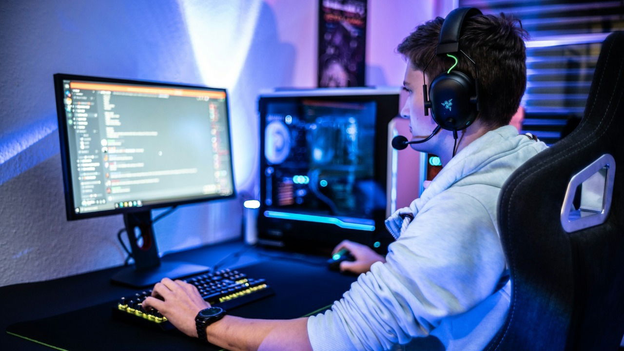 A person wearing headphones and using a gaming PC