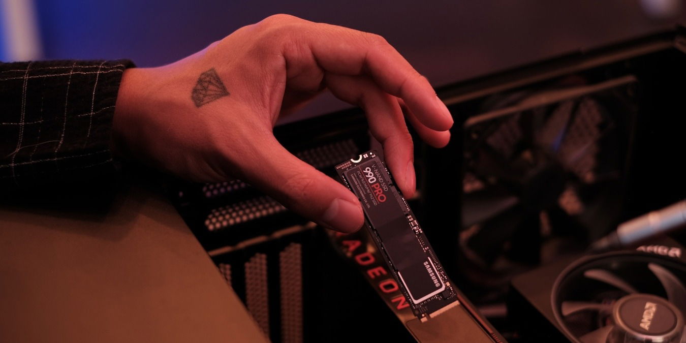 Hand holding a black Samsung SSD near an open PC