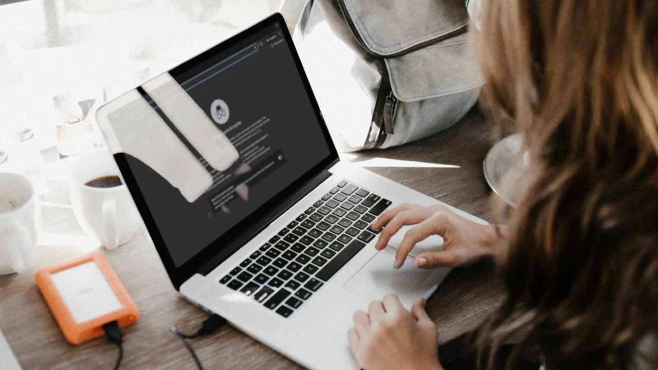 A photograph of a woman using a laptop on a top of a table.