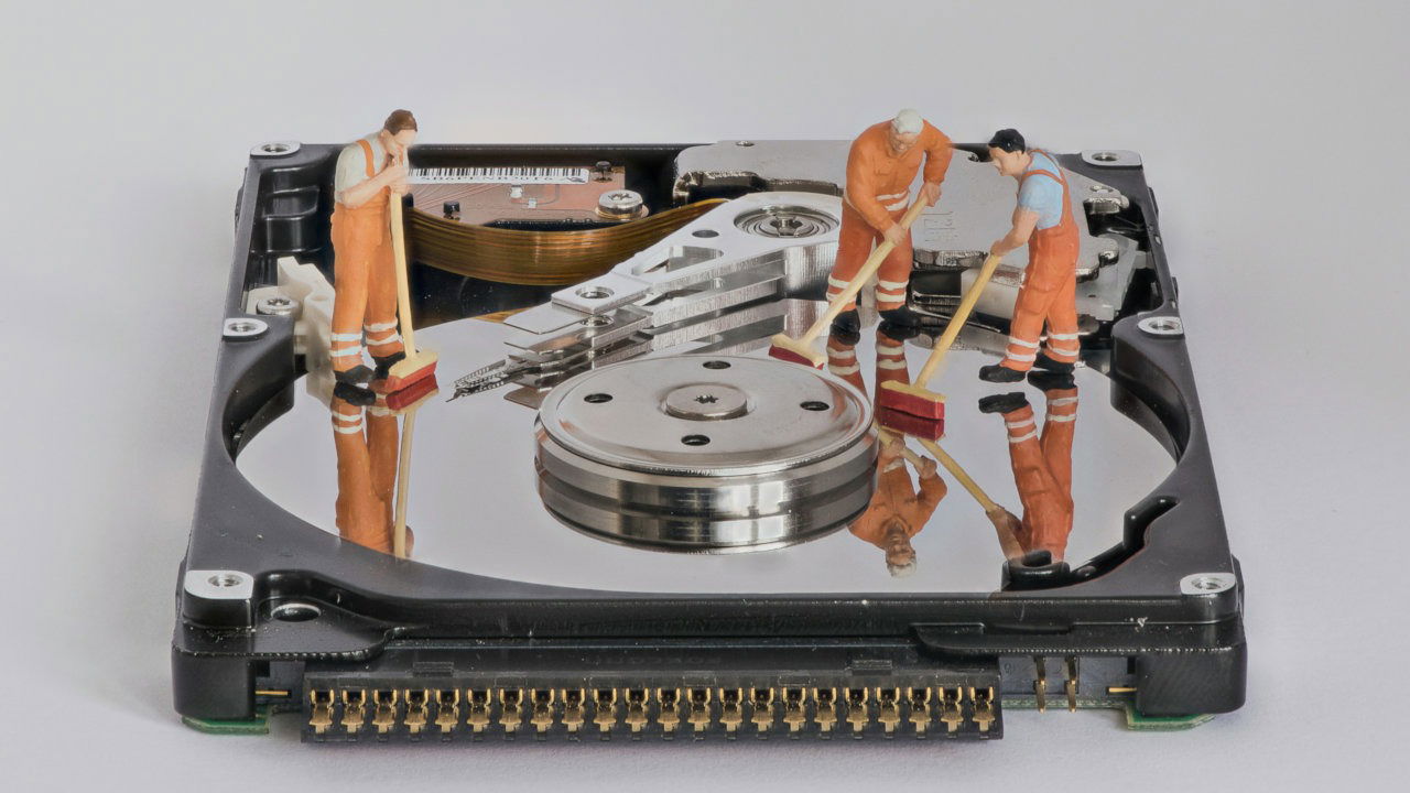 A photograph of a slim hard disk with miniature figures on top of it.