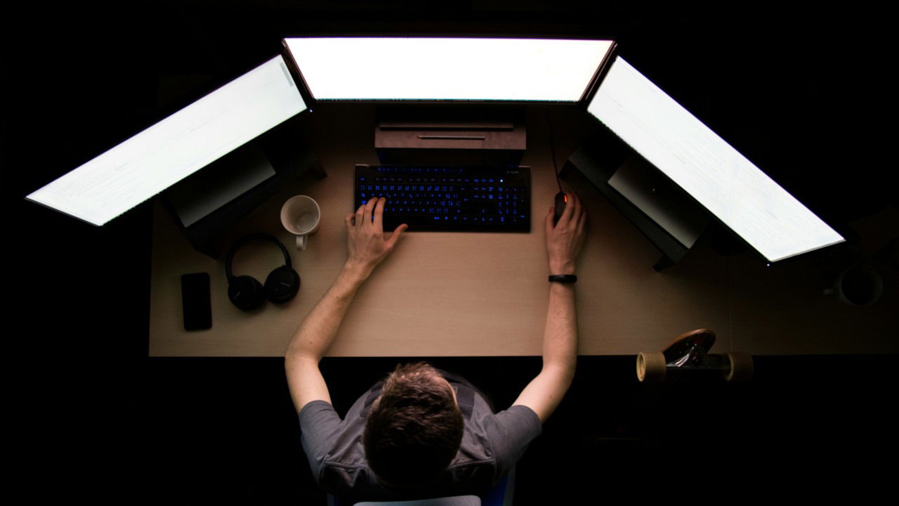 A photograph of a person working on a computer desk.