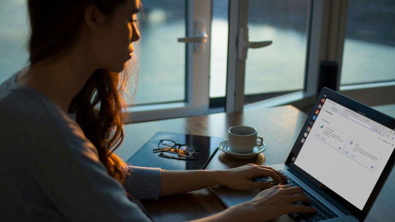 A photograph of a woman using her laptop on top of a table.