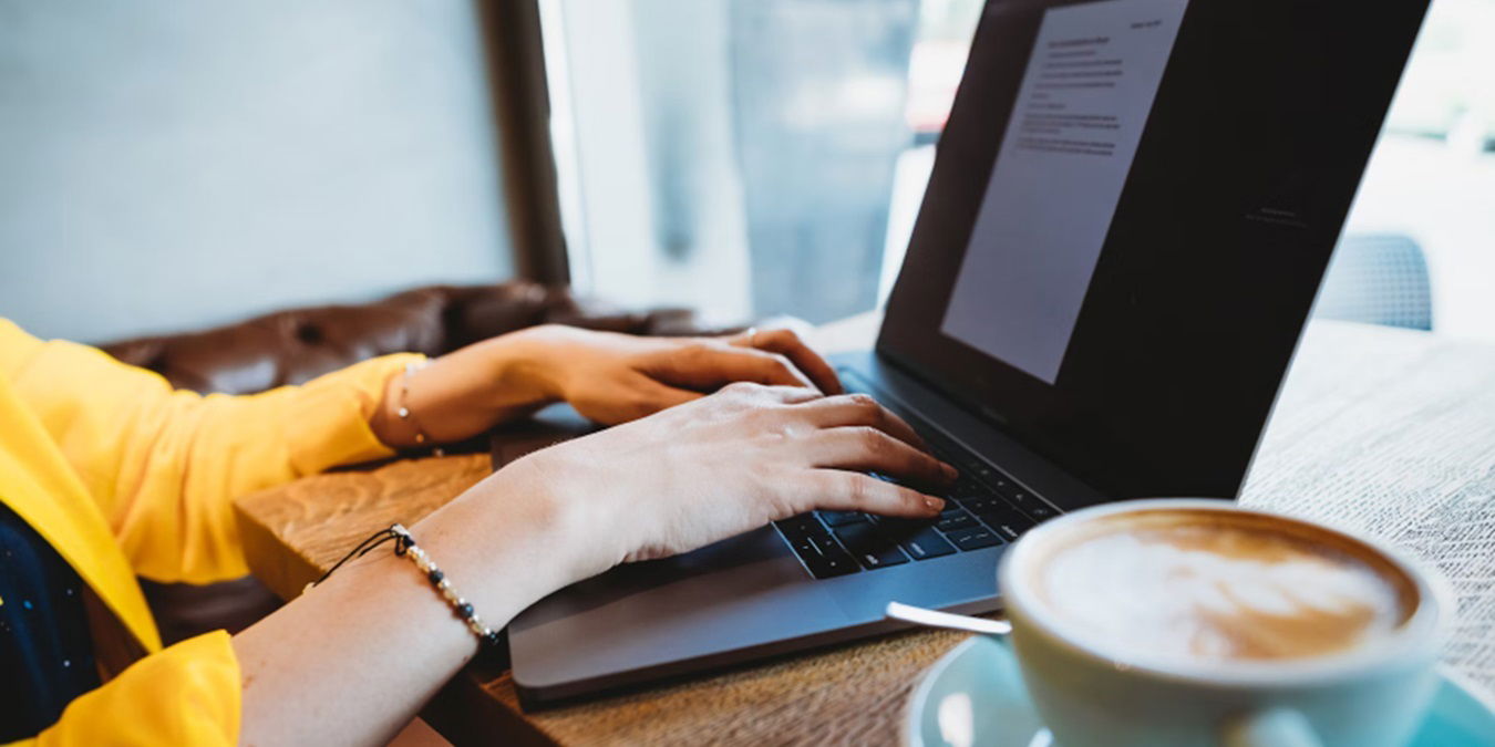 Person working at laptop with a cup of coffee.