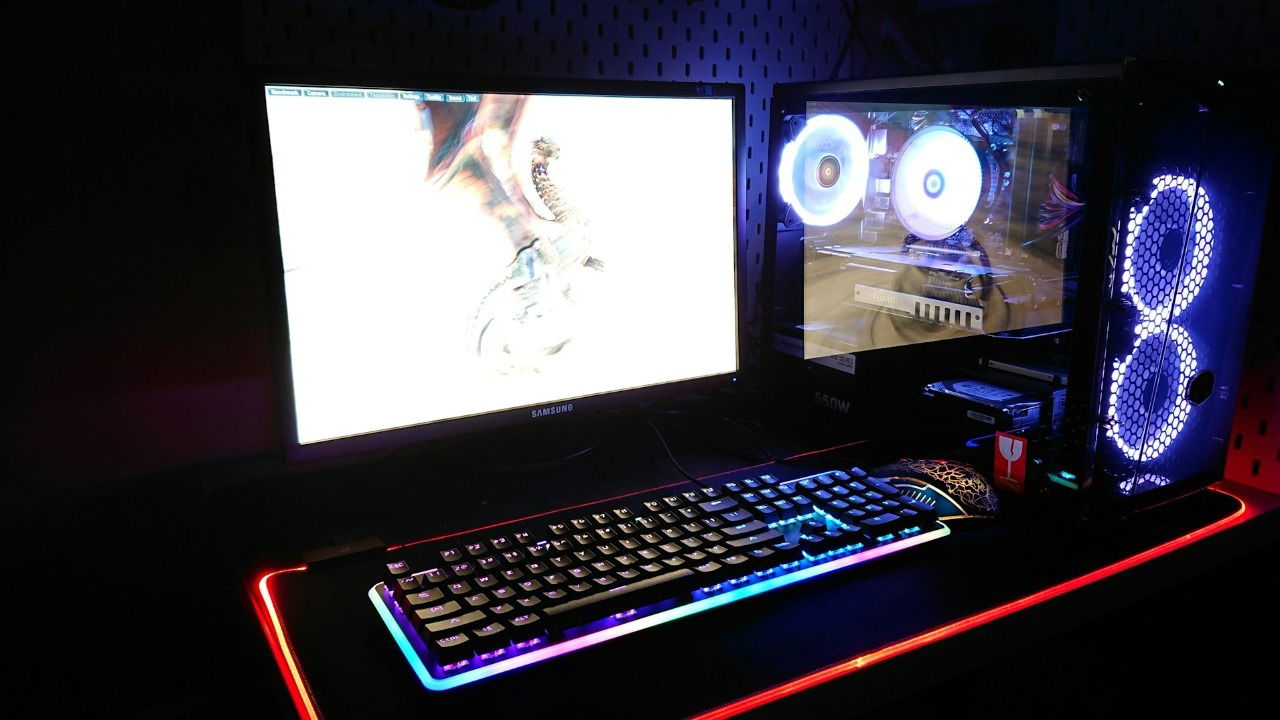 Gaming PC desk setup showing a PC, monitor, keyboard, and mouse with RGB lighting