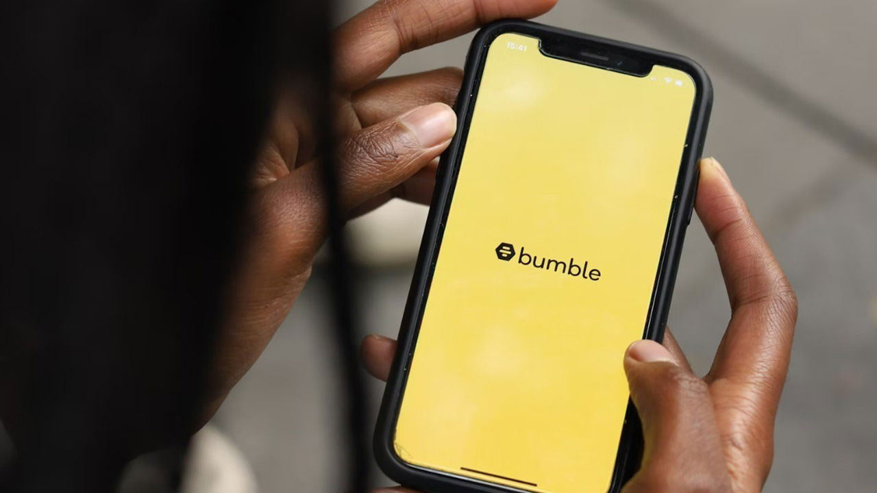 Woman's hand holding a phone with the Bumble app.