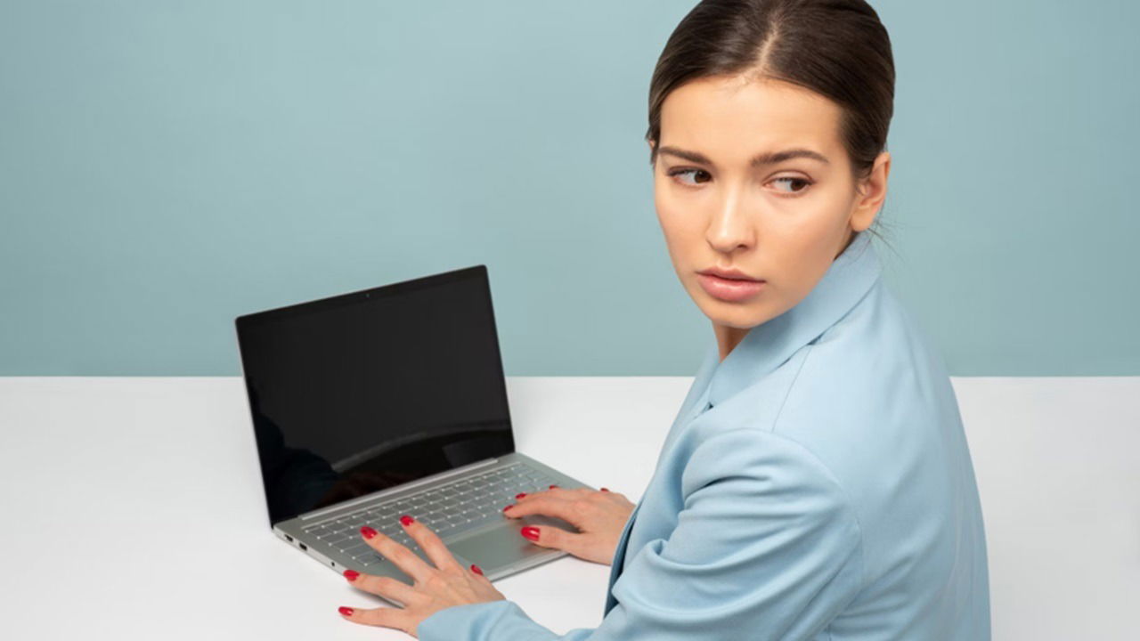 A woman sneaking onto a laptop.