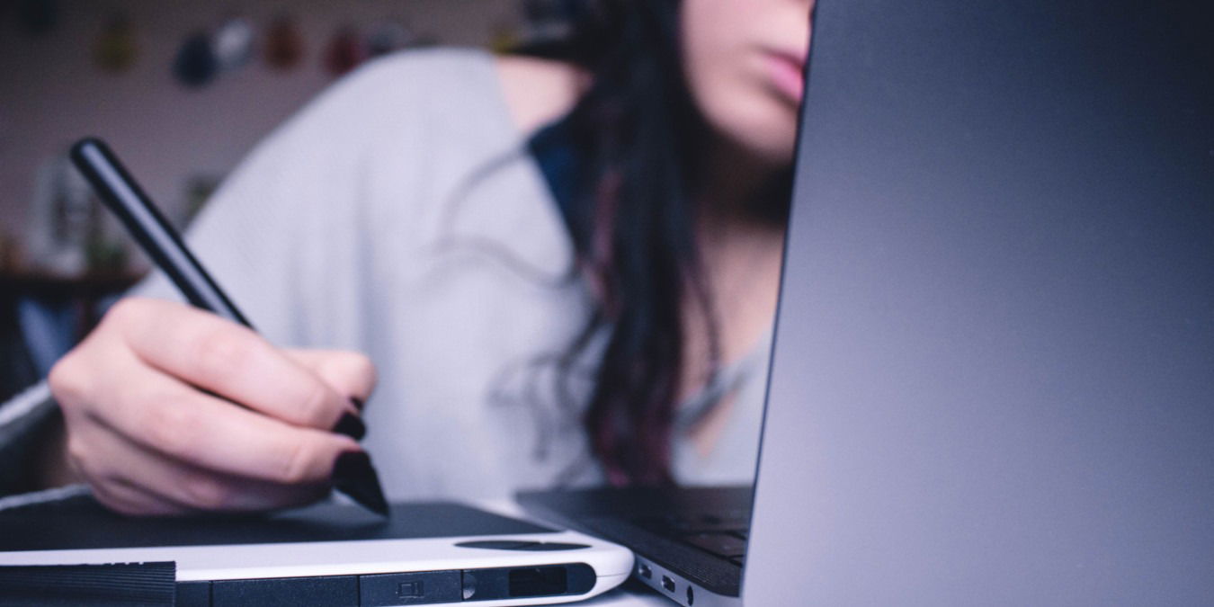 A photograph of a woman drawing on a computer tablet.