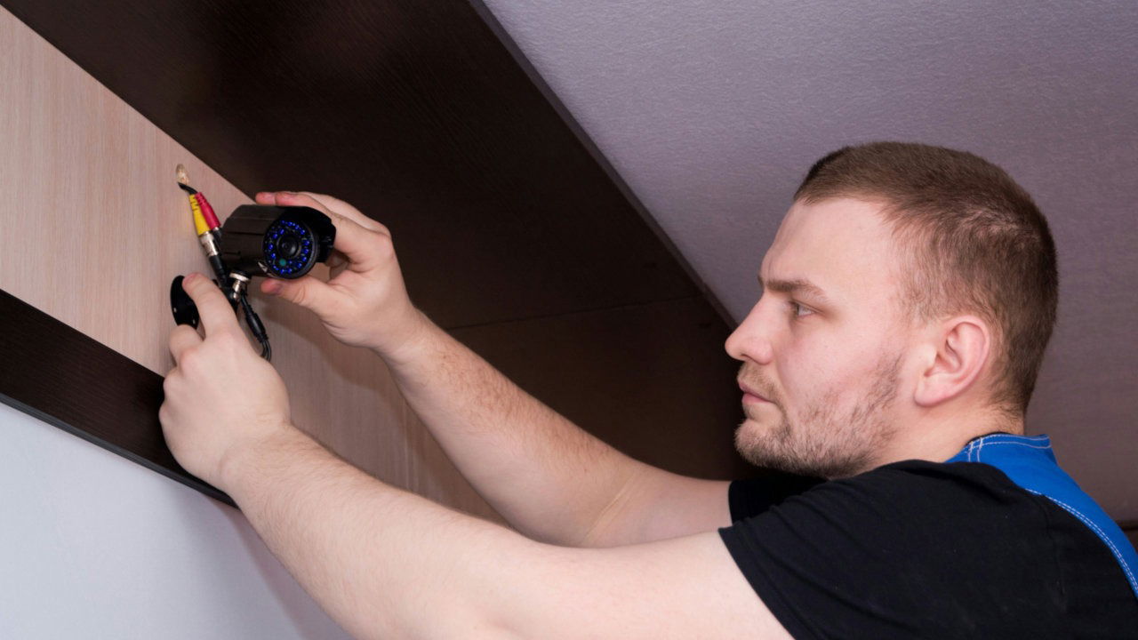 A photograph of a person fixing a security camera.