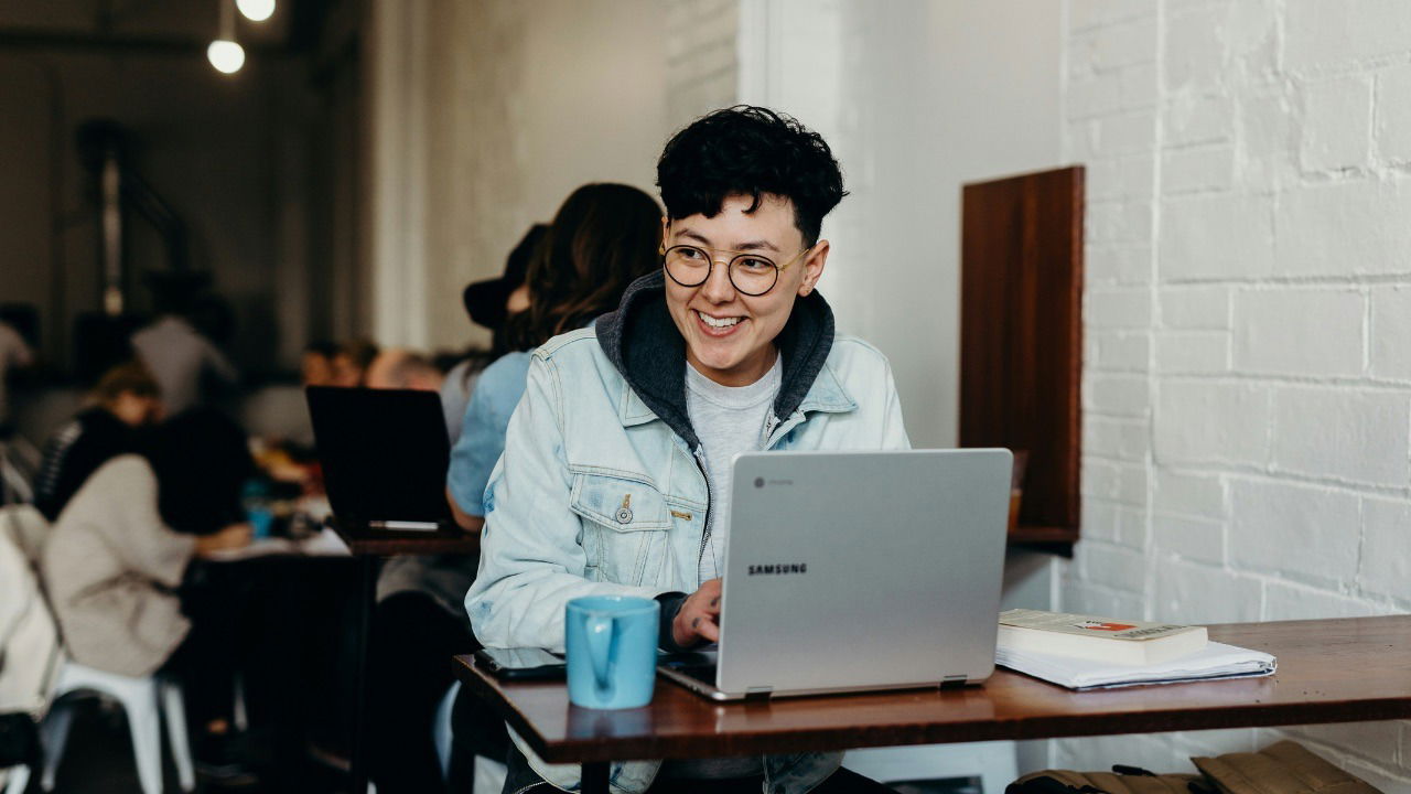 A person working on their computer with books on the table