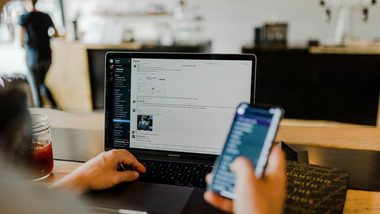 A person using instant messaging on their mobile device and laptop