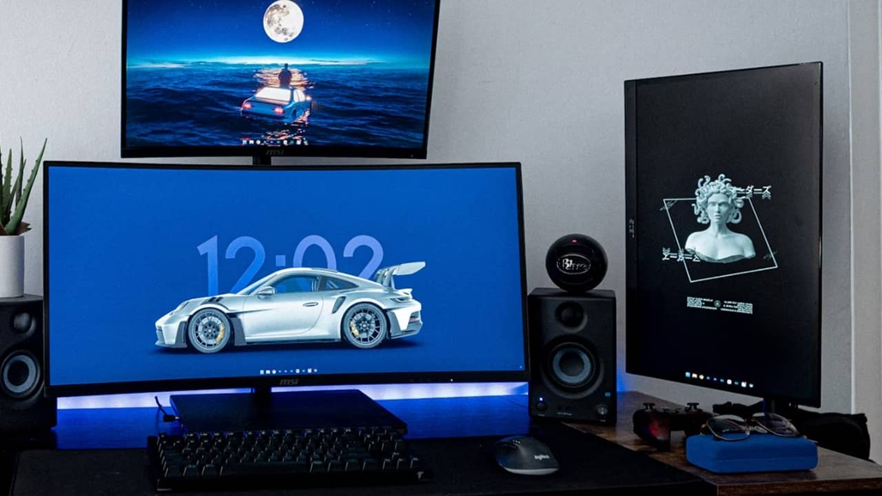 Three monitors setup on a desktop with keyboard.