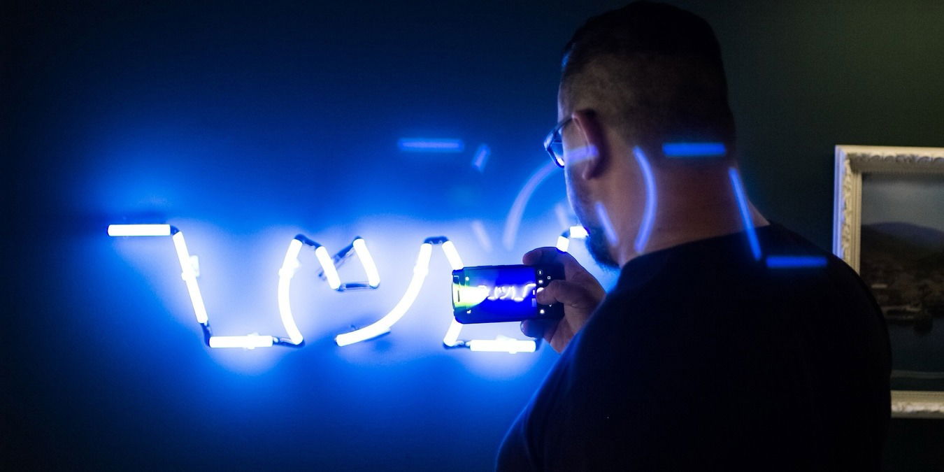 Man taking a photo of a neon sign